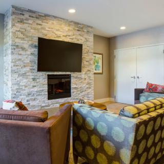 A modern living room with a stone fireplace and mounted television, featuring comfortable sofas in a cozy setting.