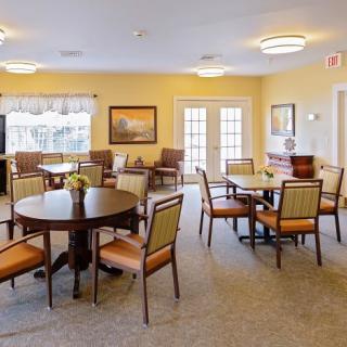 A brightly lit dining area with several tables and chairs arranged neatly in a cozy setting.