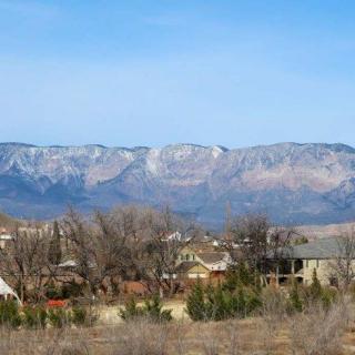 A serene rural landscape with a mountain range in the background under a clear blue sky.