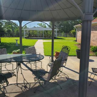 A serene patio setting featuring a gazebo, table, and chairs, perfect for enjoying a sunny day in the garden.