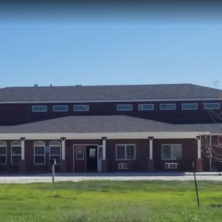 A brick building with a modern design, possibly a school, surrounded by grass on a sunny day.