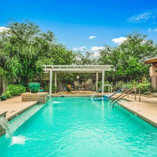 A serene backyard oasis featuring a sparkling swimming pool under a clear blue sky.