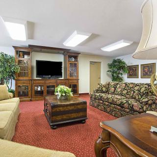A cozy living room featuring a patterned sofa, wooden coffee table, and entertainment center with a television.