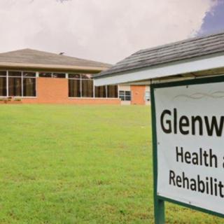 A rehabilitation center with a sign in the foreground reading 'Glenwood Health and Rehabilitation'.