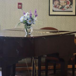 A grand piano adorned with a vase of flowers in a cozy interior setting.