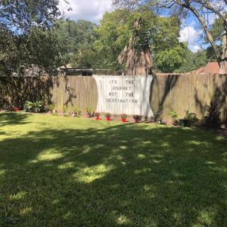 A backyard with a fence displaying a large sign on a sunny day.