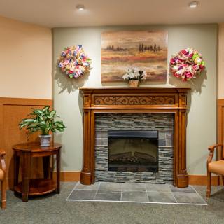 A cozy living room corner featuring a decorative fireplace, artwork, and plants.