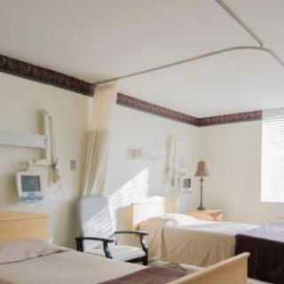 A bright hospital room with two beds and medical equipment.