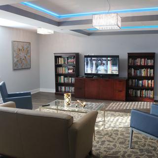 A modern living room featuring comfortable seating, bookshelves, and a television.