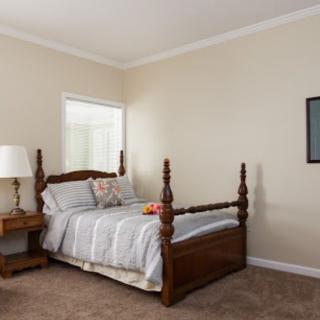 A cozy bedroom with a wooden bed frame, nightstand, and a lamp.