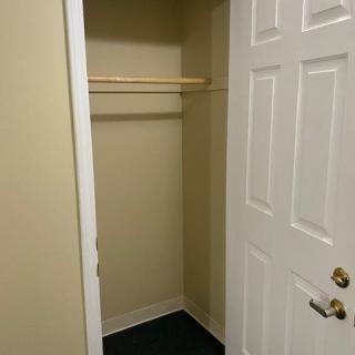 An empty closet with a wooden rod and an open door.