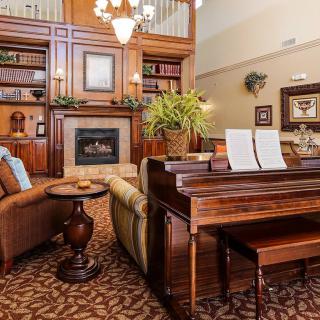 A cozy living room with a piano, fireplace, and bookshelves.