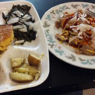 A delicious spread featuring leafy greens, corn bread, roasted potatoes, and a savory dish.