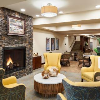 A cozy living room with a fireplace and modern decor features yellow chairs and stylish furnishings.