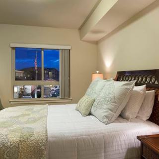 A cozy bedroom featuring a neatly made bed, soft pillows, and a window that offers a view of the evening sky.
