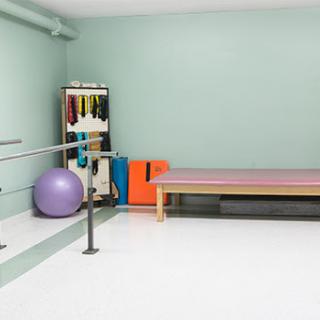 A well-equipped rehabilitation space with exercise equipment, including a stability ball and therapy table.