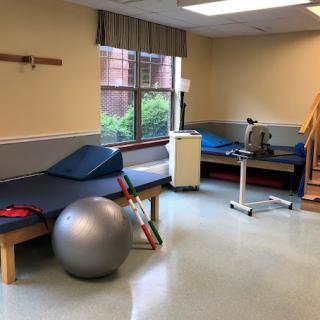 A physical therapy room equipped with exercise equipment, including a therapy ball and treatment tables.