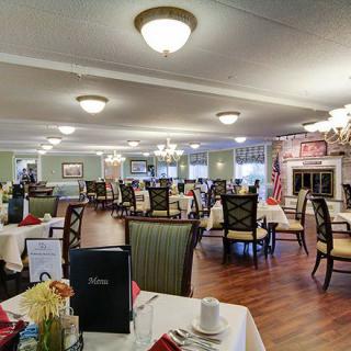 An elegant dining room with neatly arranged tables and chairs, featuring warm lighting and decorative elements.