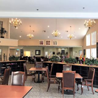 A spacious dining area with elegant chandeliers and neatly arranged tables and chairs.