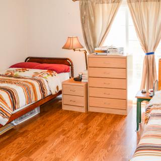 A cozy bedroom with two single beds, a small lamp, and wooden furniture on a wooden floor.