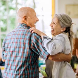 An elderly couple joyfully dancing together at home.