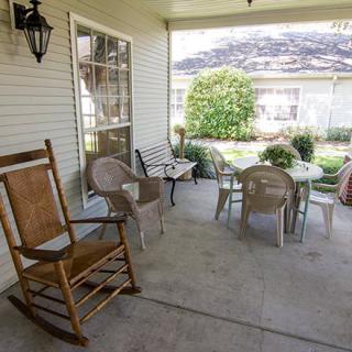 A cozy porch with rocking chairs and outdoor seating overlooking a garden.