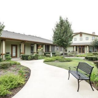 A peaceful garden with a paved pathway, surrounded by buildings and greenery.