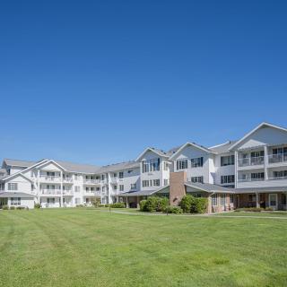 A large residential building with a well-maintained lawn under a clear blue sky.