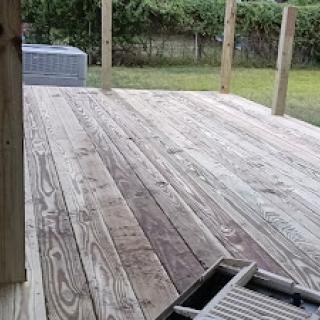 A wooden deck featuring weathered planks and an open outdoor area.