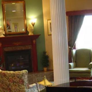 A cozy living room with a fireplace, elegant furniture, and a decorative column.