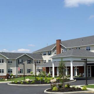 Exterior view of a residential building with landscaped lawn under a blue sky.