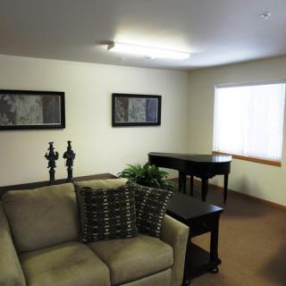 A cozy living room with a sofa, piano, and decorative artwork on the walls.