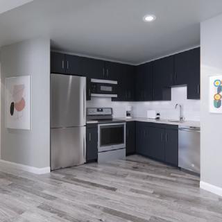 A modern kitchen features sleek gray cabinets, stainless steel appliances, and a hardwood floor.