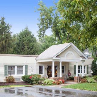 A quaint residential house with a porch surrounded by greenery.