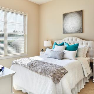 A bright and cozy bedroom featuring a modern bed with decorative pillows and ample natural light.