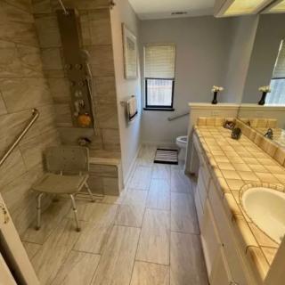 A bathroom with a shower, sink, and tiled flooring.
