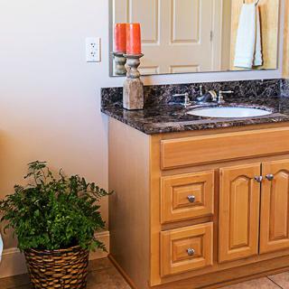 A bathroom vanity with a granite countertop, decorated with a plant and candle.