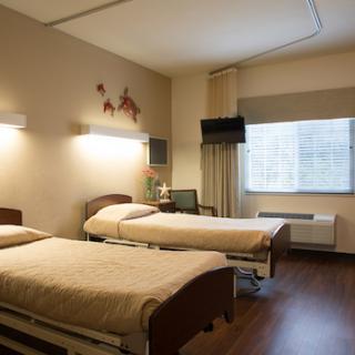 A spacious patient room in a hospital featuring two beds and modern amenities.