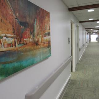 A vibrant piece of artwork adorns the wall of a well-lit hallway.