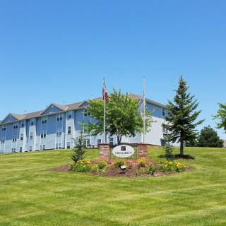 A hotel building surrounded by a well-maintained lawn and trees under a clear blue sky.