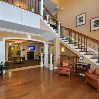 A spacious lobby area featuring a grand staircase and elegant wooden flooring.