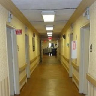 A hospital corridor with doors on either side and a person in the distance.