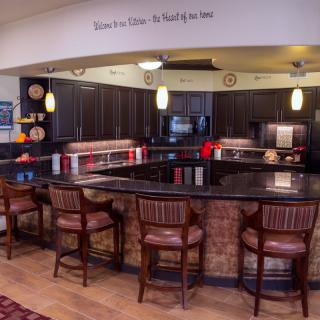 A cozy kitchen interior featuring a counter with stools and pendant lighting.