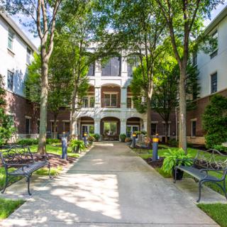 A peaceful courtyard with benches and trees in front of a residential building.