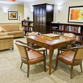 A cozy interior with a table, chairs, bookshelves, and artwork.