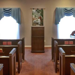 An interior view of a small chapel with wooden pews and a central pulpit.
