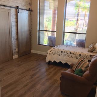A cozy bedroom with a small bed, armchair, and large windows letting in natural light.
