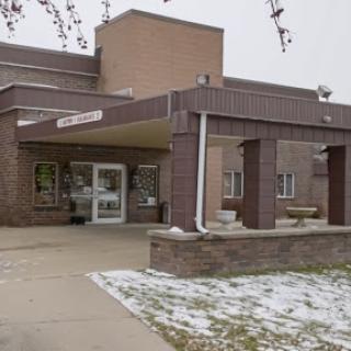 A view of the entrance to a building during winter, with some snow on the ground.