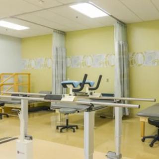 A room equipped for physical therapy with parallel bars and exercise equipment.