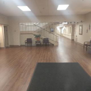 A spacious interior hallway with wooden flooring and a staircase in the background.